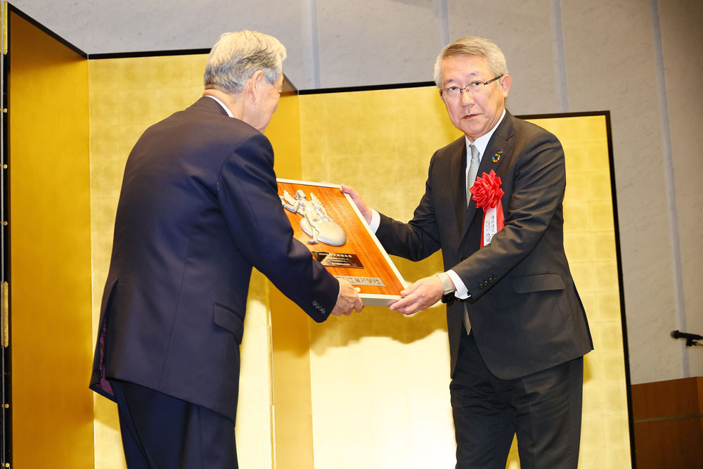 日刊工業新聞社井水社長（左）から表彰盾を受け取るスポーツベット 野球池田副社長（右）