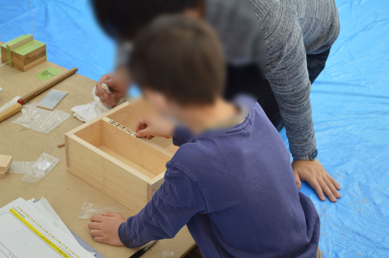 組み立てた作品にデコレーションを行う親子