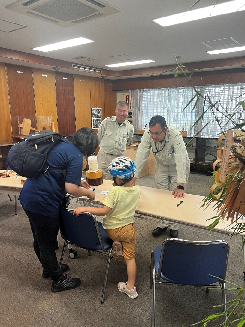 木の短冊に願い事をかく親子（東京木工場）