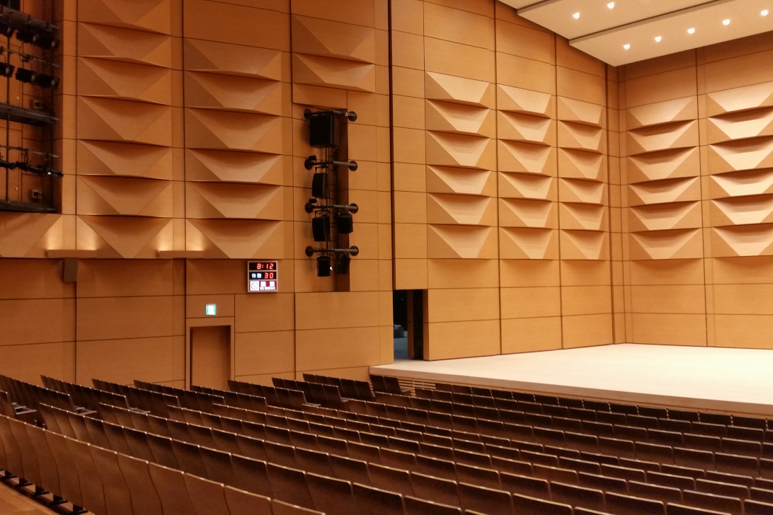 市の木「山ざくら」をイメージしたメインホール 腰壁のランダムリブ板が豊かな音響を生み出し、演劇から演奏会までさまざまな演目に対応しています