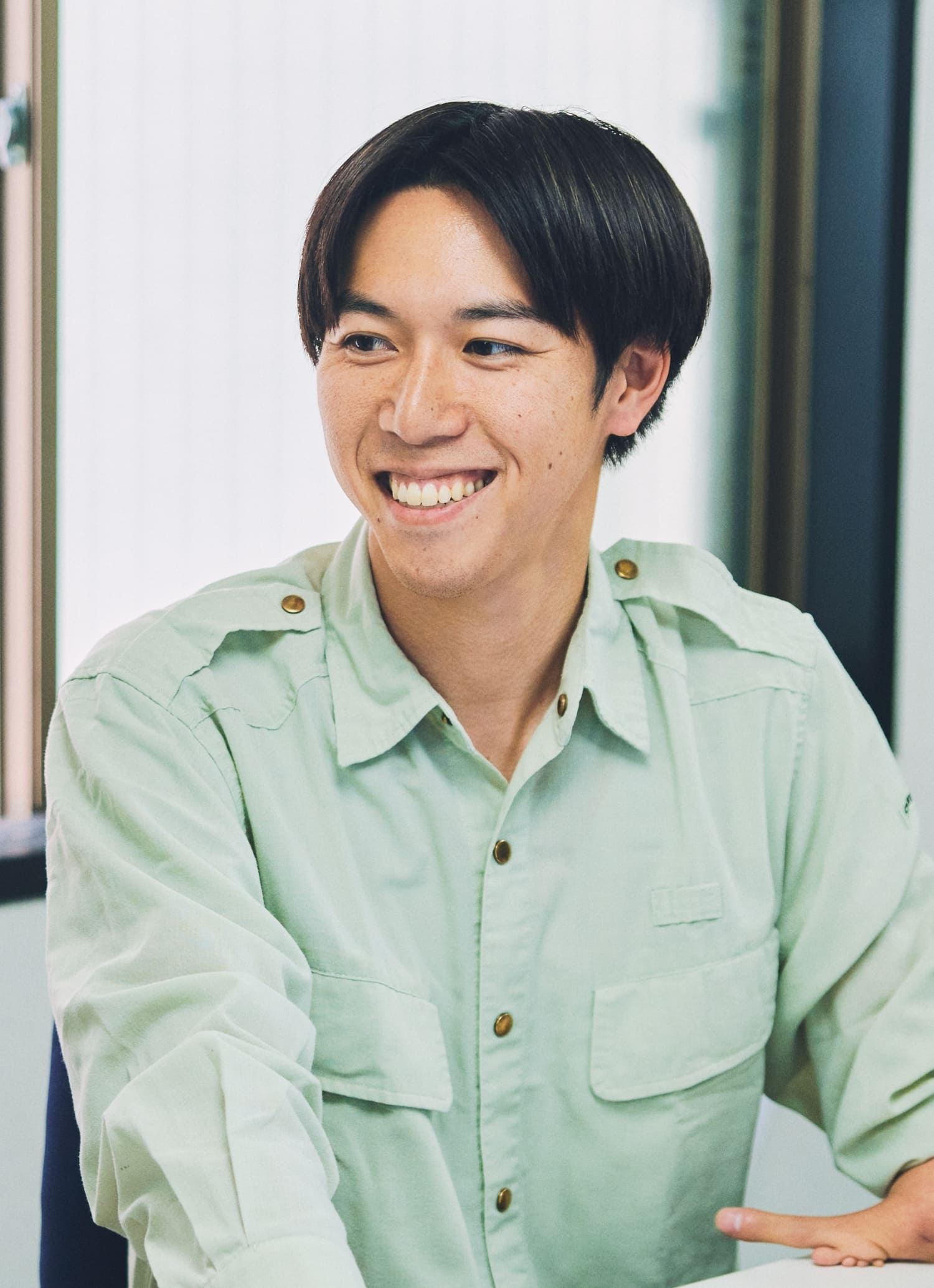 現場の事務所にて上肢スポーツベット サッカー 夏期をもつ社員の階戸健太さんが同僚と談笑している様子